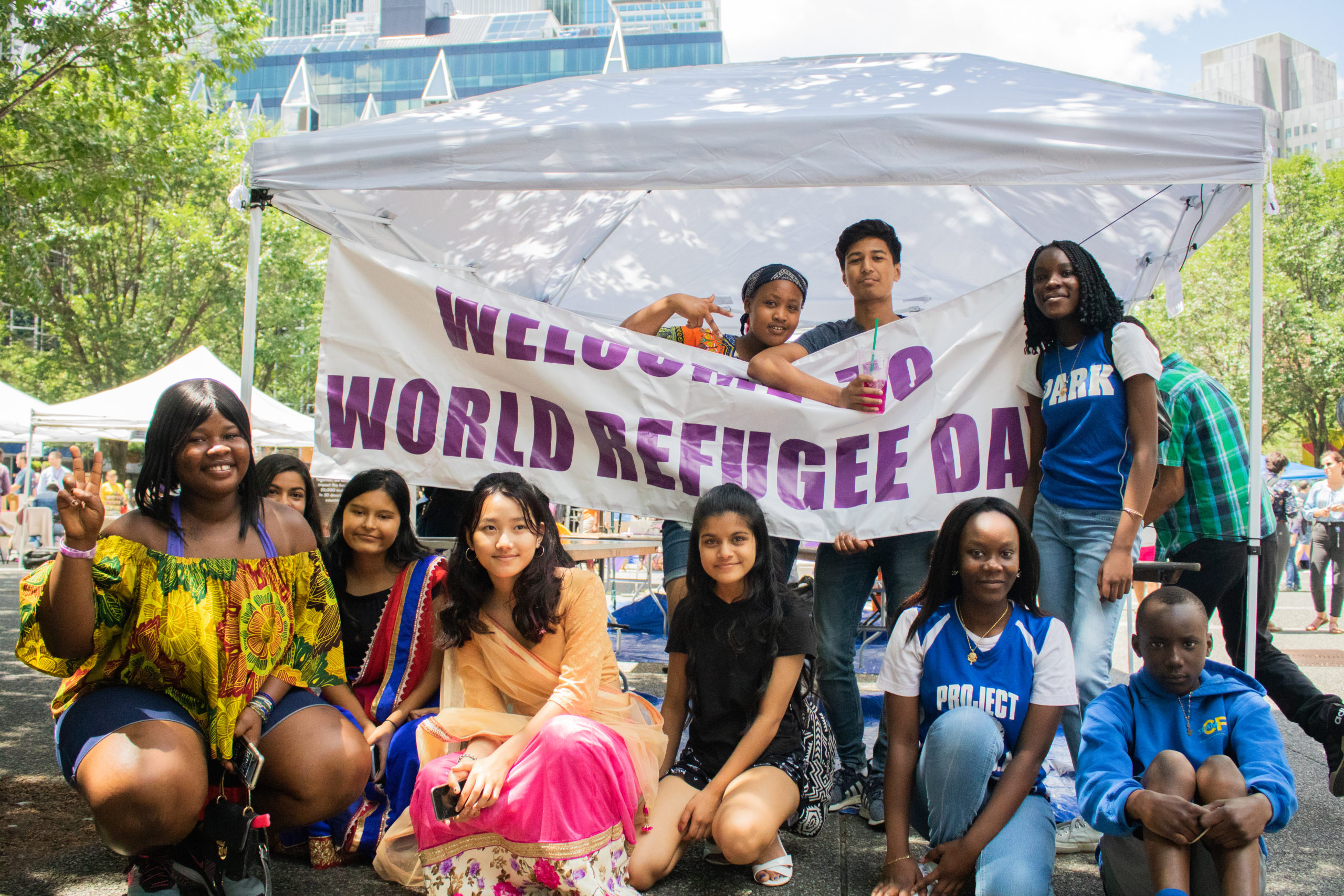 teens holding sign: Welcome to World Refugee Day